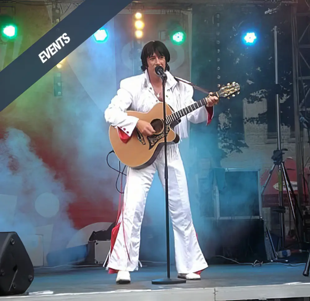 Joe Prommer in weißem Bühnen-Outfit und Gitarre